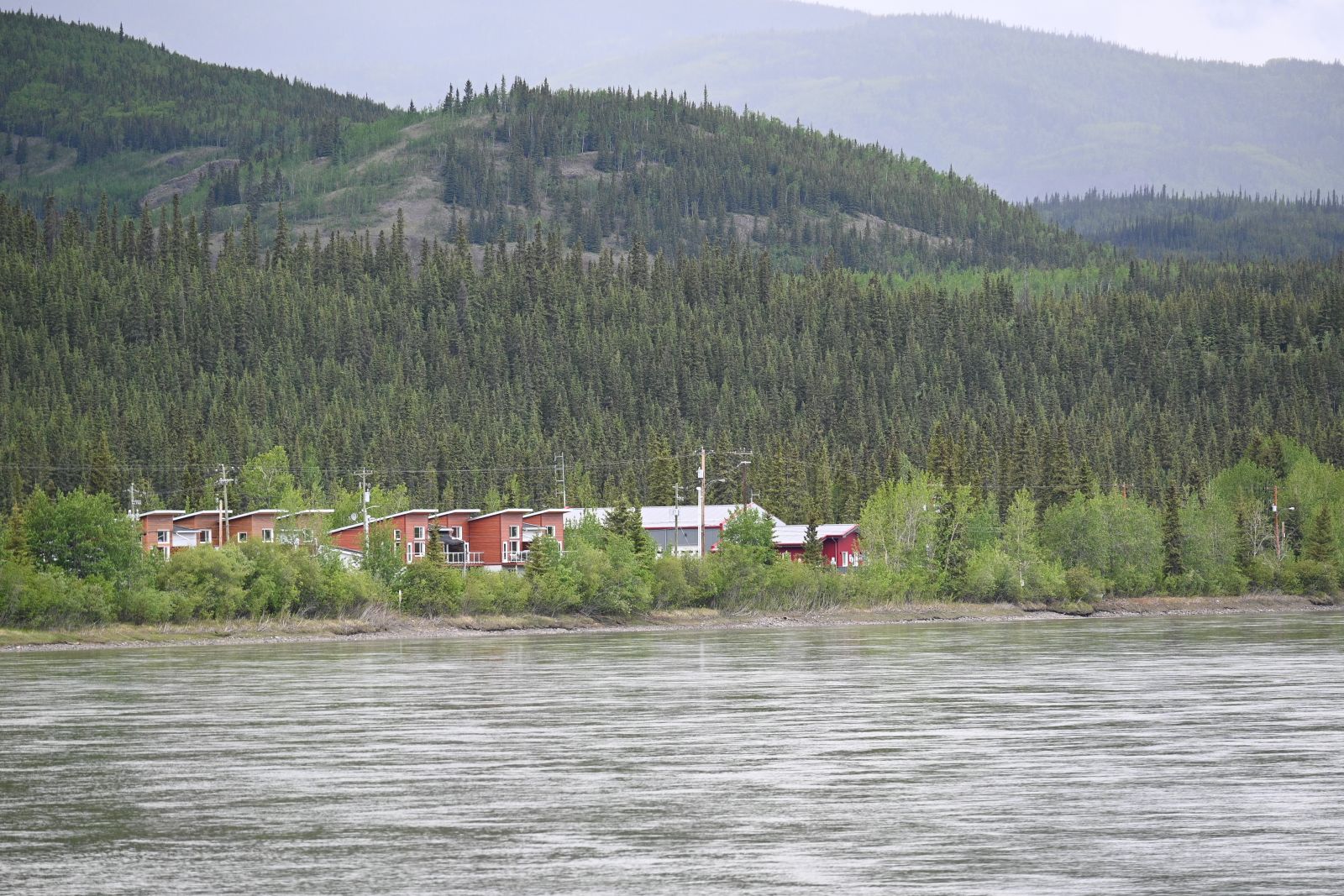 A scenic view of Carmacks shows homes alongside the Yukon River.