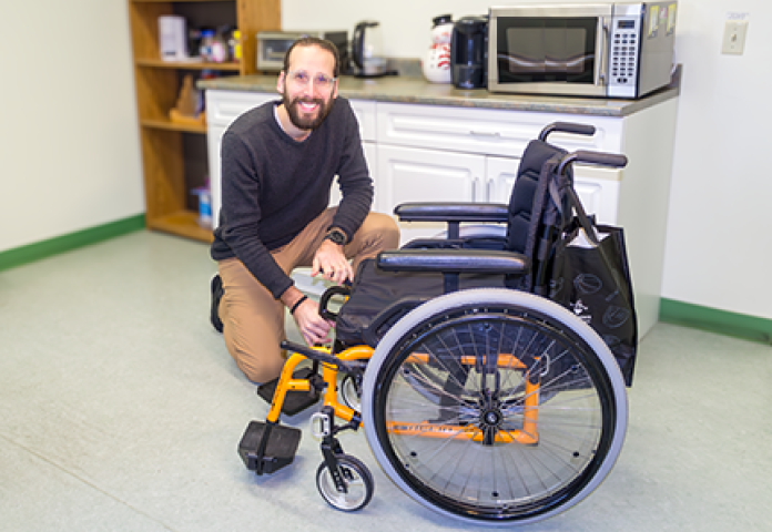 a person sitting by a wheelchair.