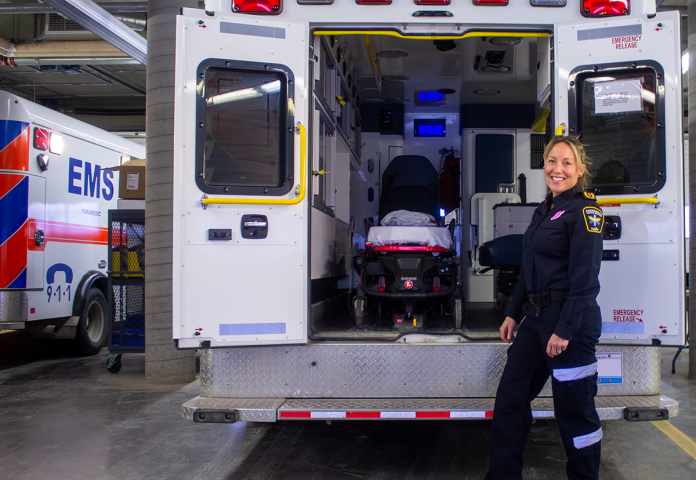 a person standing by an emergency medical service truck.