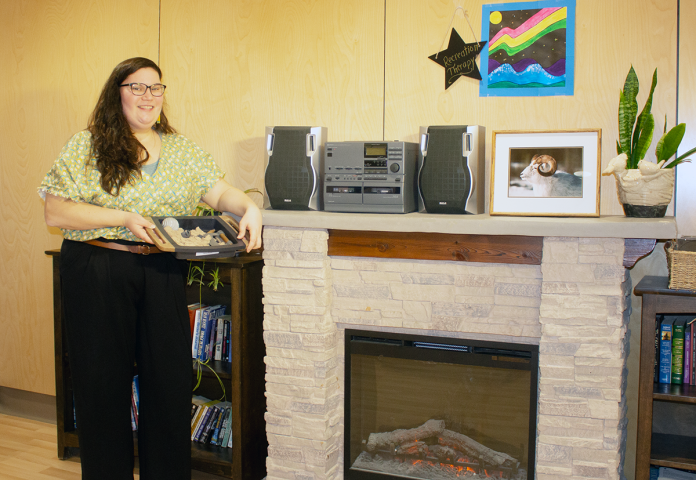 a person standing by a fireplace holding a tray.