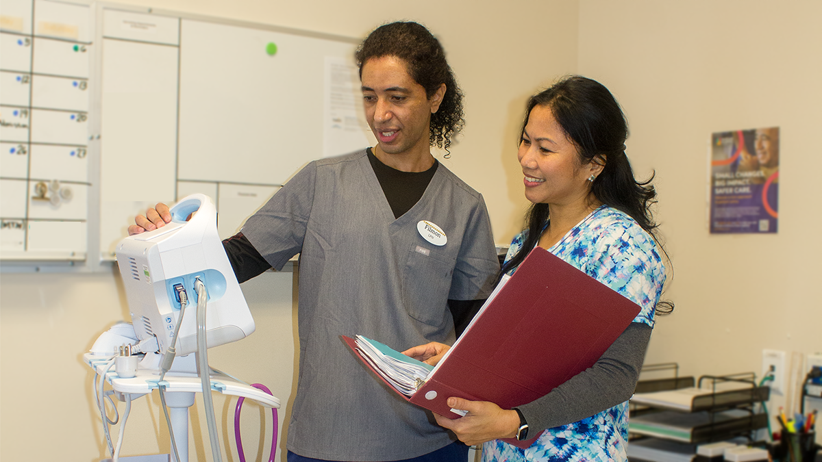 2 people standing by a medical equipment.