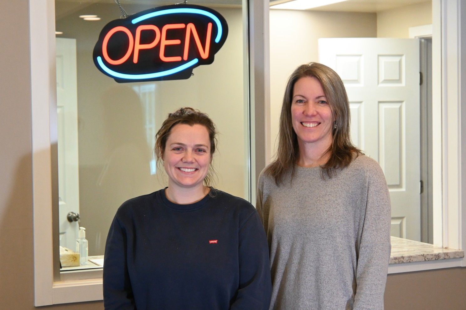 2 people standing in front of "open" sign