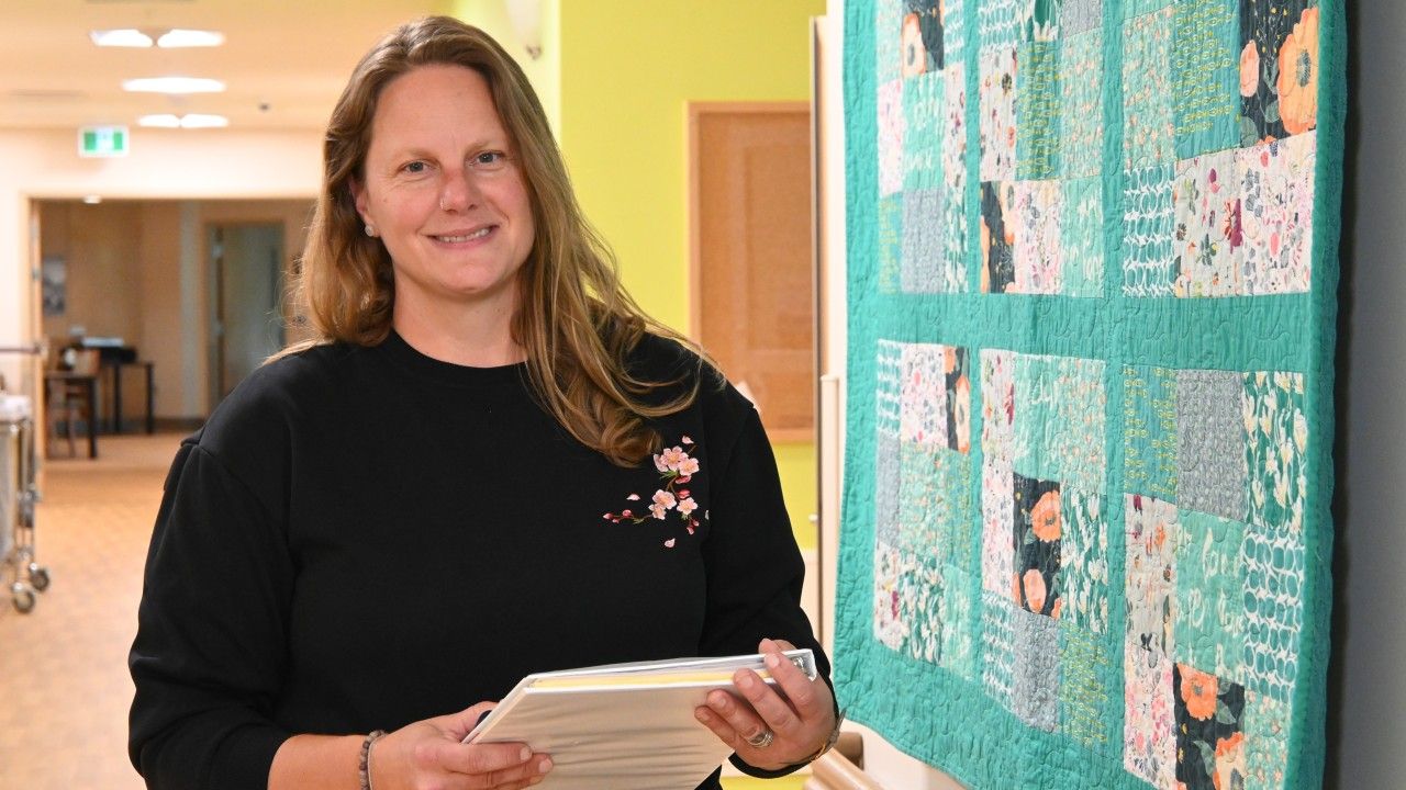 Jill standing by a hanging quilt