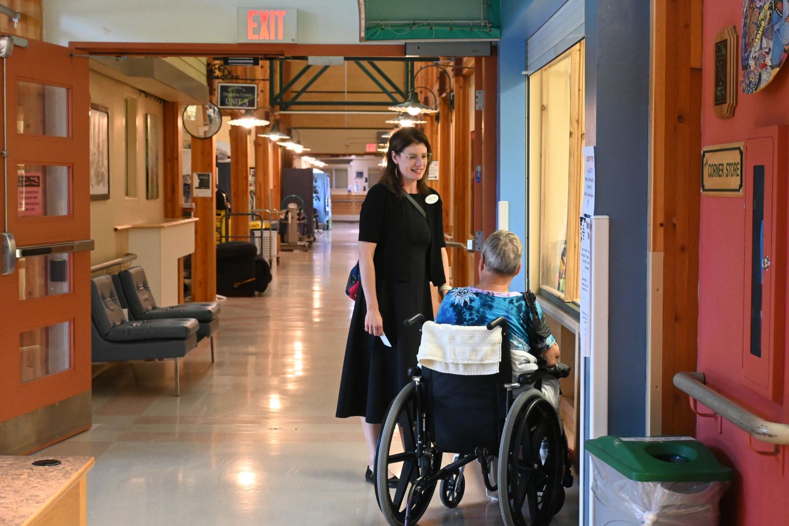 a person standing by an elder in wheelchair 