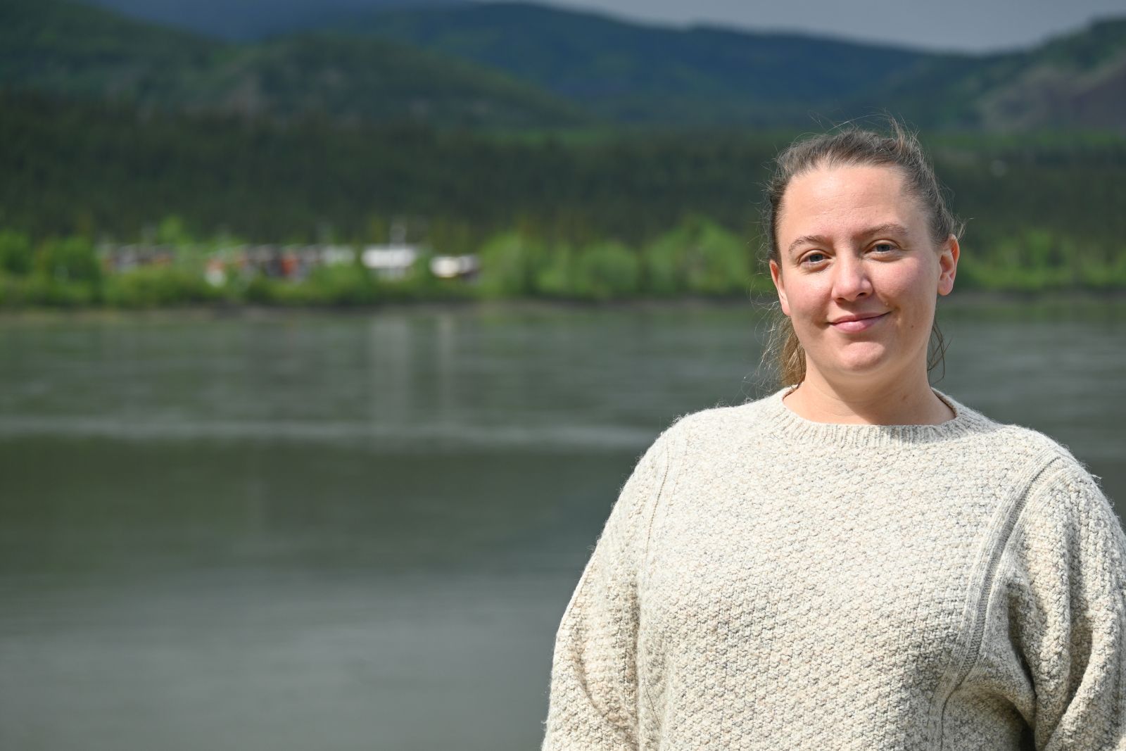 A nurse stands on the shore of the Yukon River in Carmacks, Yukon