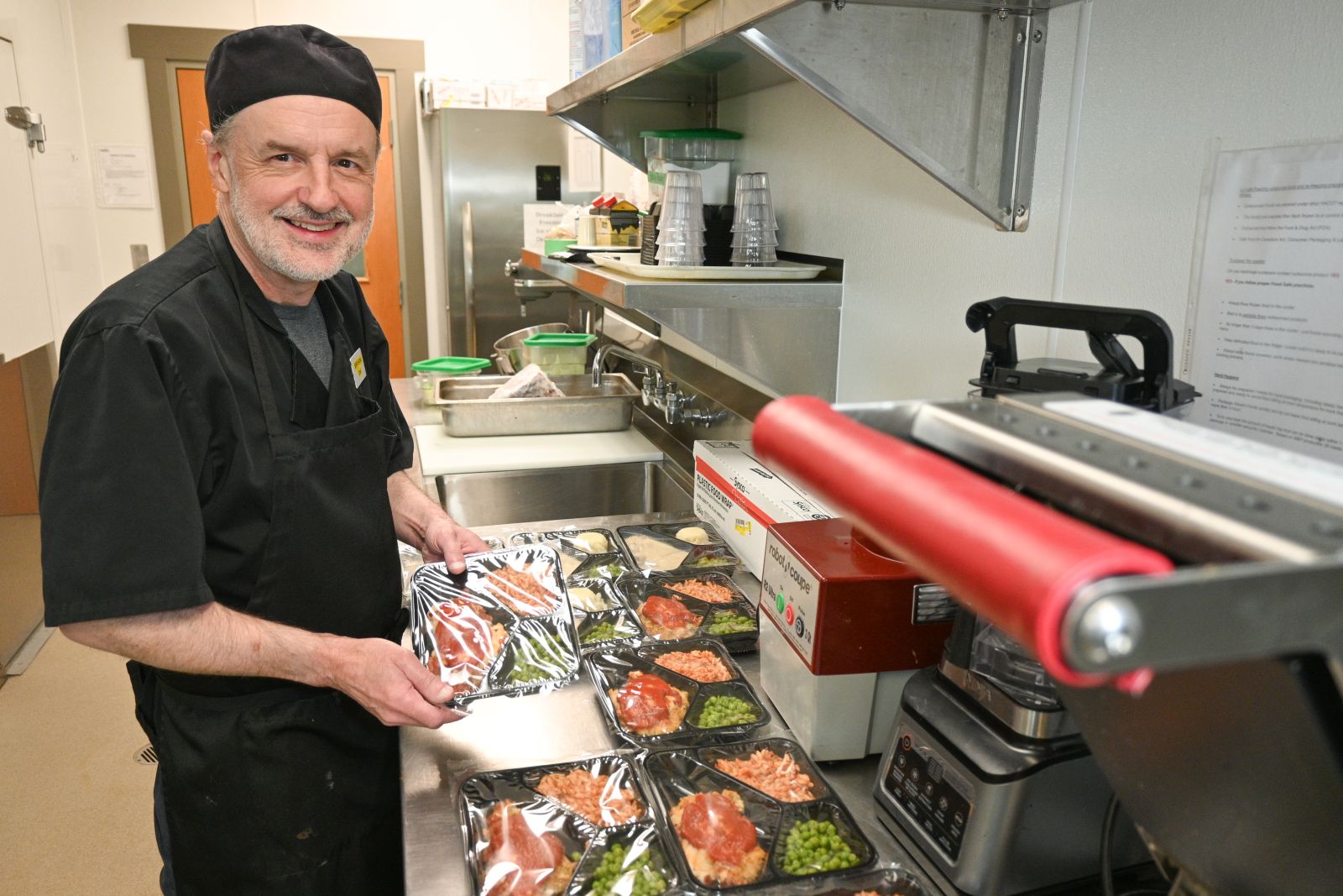 A cook is seen in the kitchen at Alexander McDonald Lodge in Dawson City surrounded by fresh ingredients