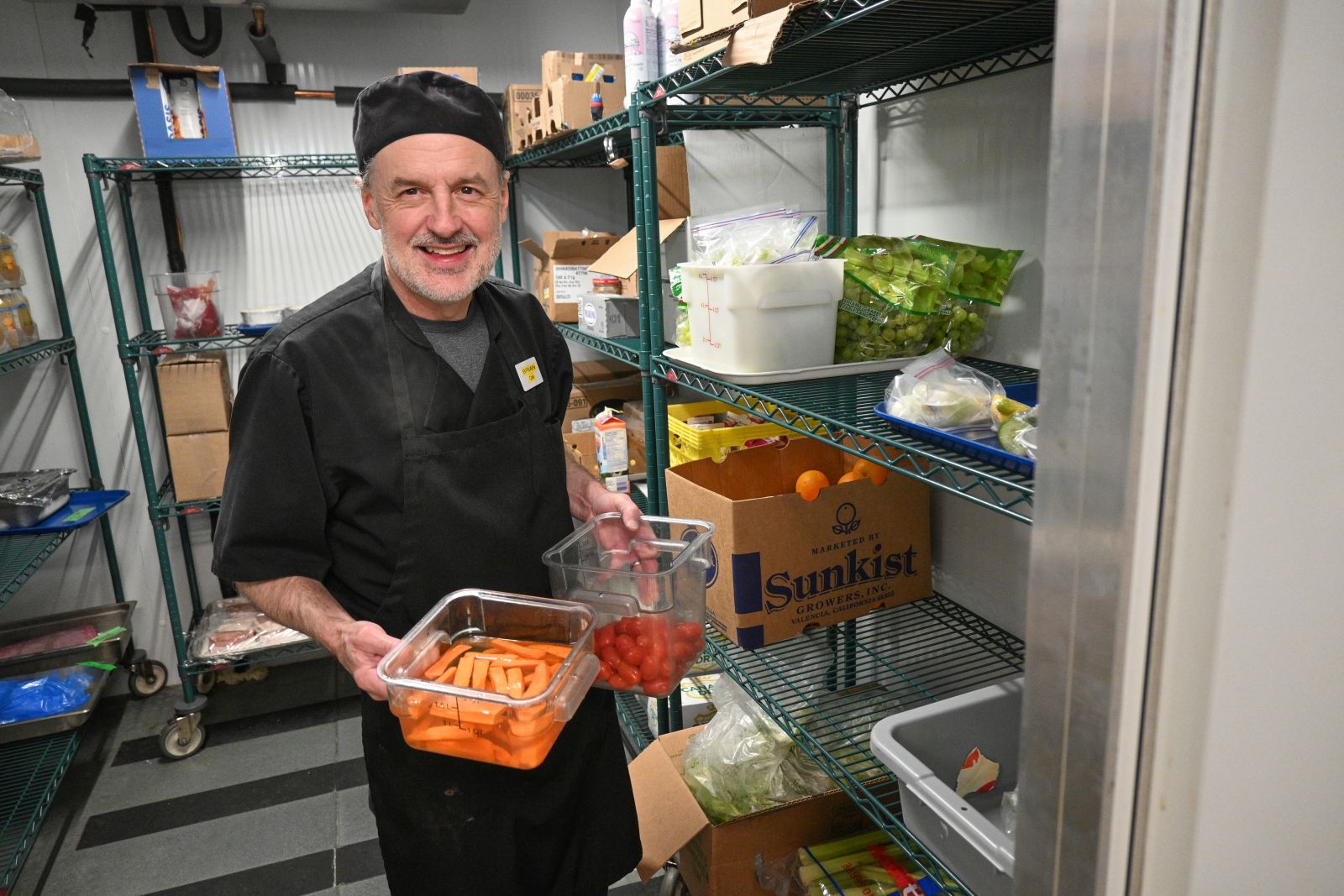 A cook is seen in the kitchen at Alexander McDonald Lodge in Dawson City surrounded by fresh ingredients