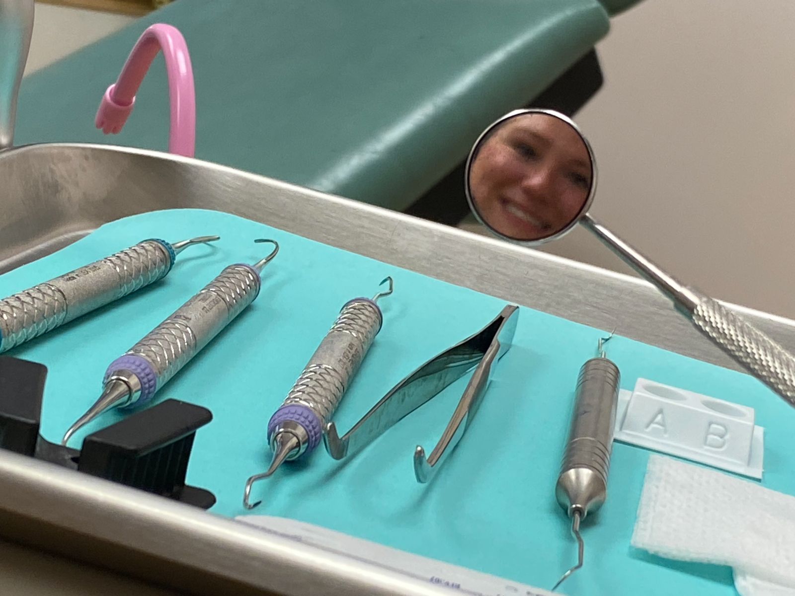 A dental hygienist is seen reflected in her instruments