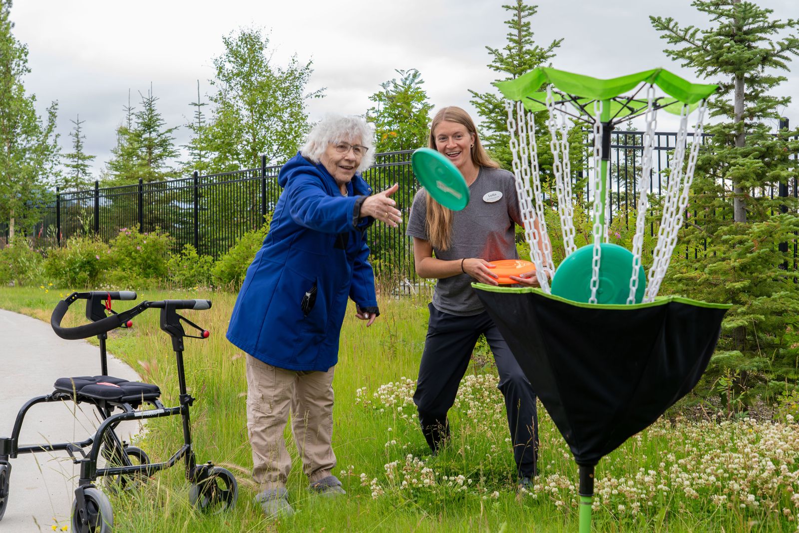 A recreation therapy assistant and resident at Whistle Bend Place play a round of disc golf