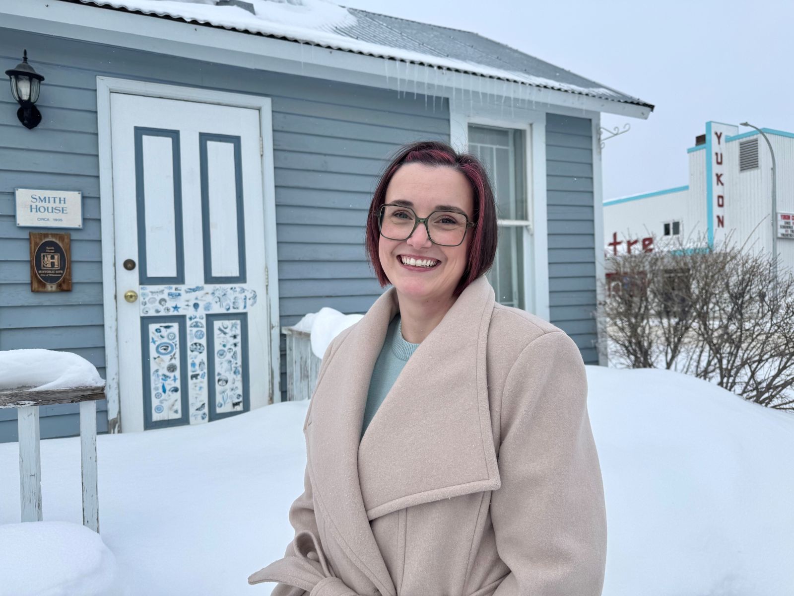 A social worker in the Yukon stands outdoors near a historic building