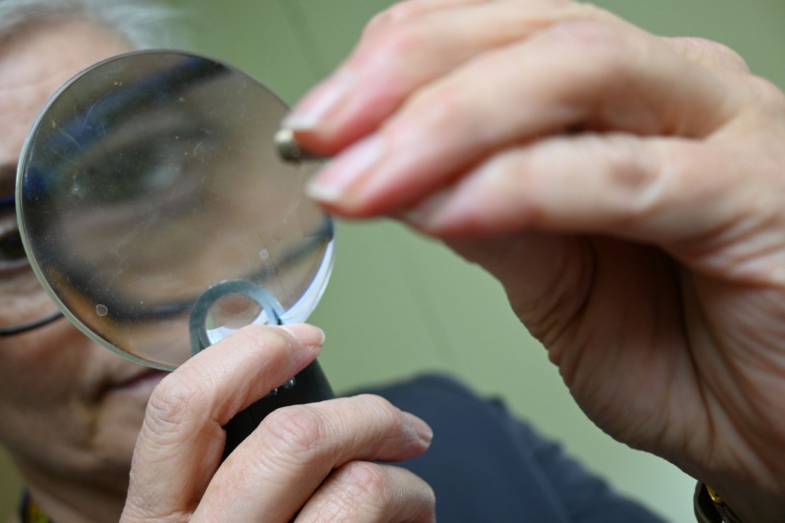 An audiologist looks at a small piece in her repair shop