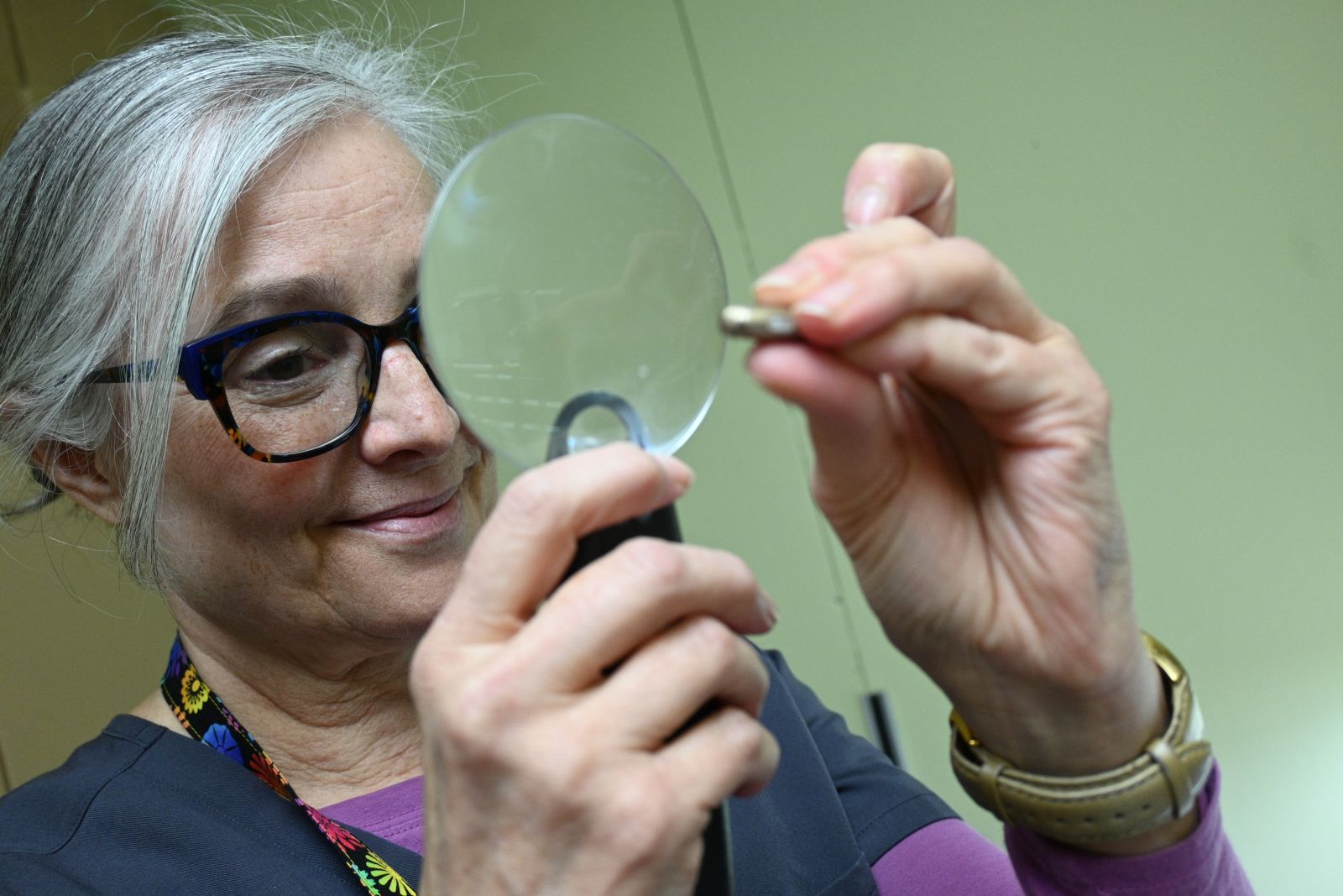 An audiologist looks at a small piece in her repair shop
