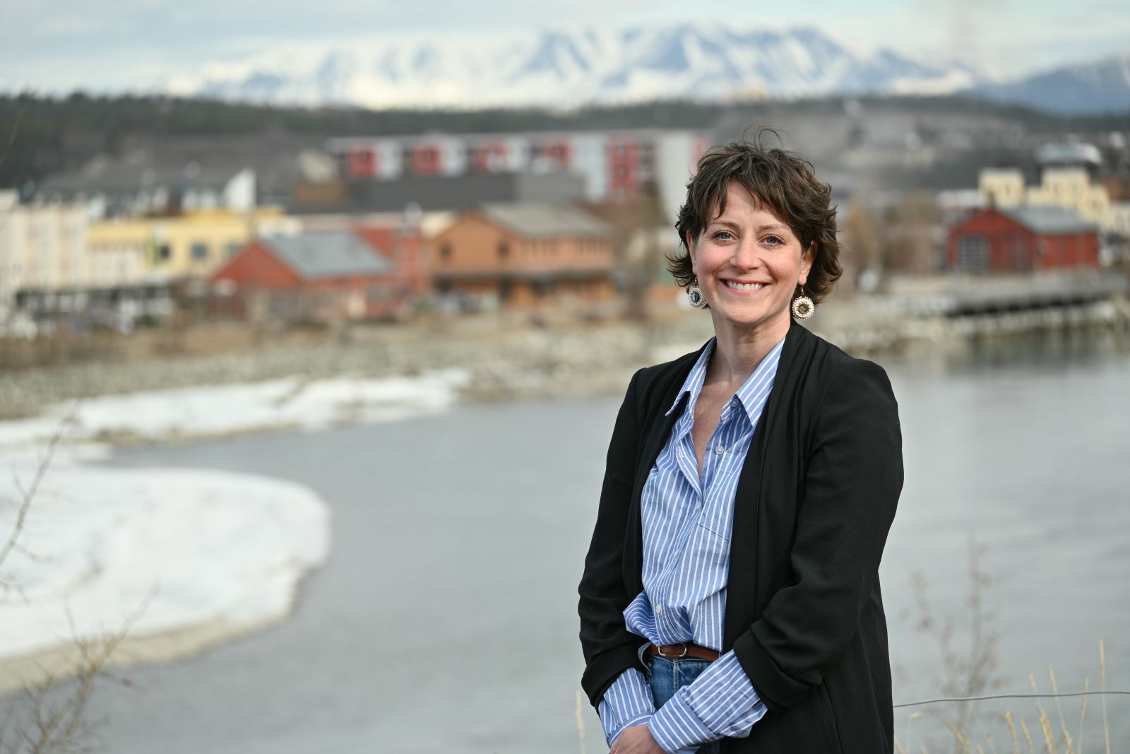 A nurse practitioner stands in Whitehorse with the Yukon River in the background