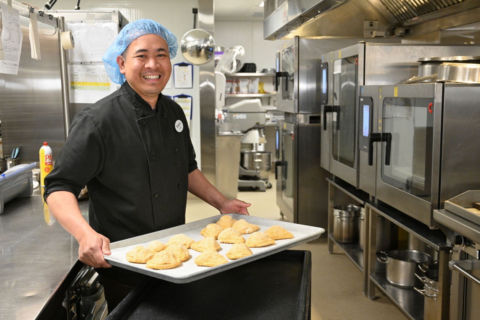 A cook in the kitchen of Whistle Bend Place preparing a chicken dinner