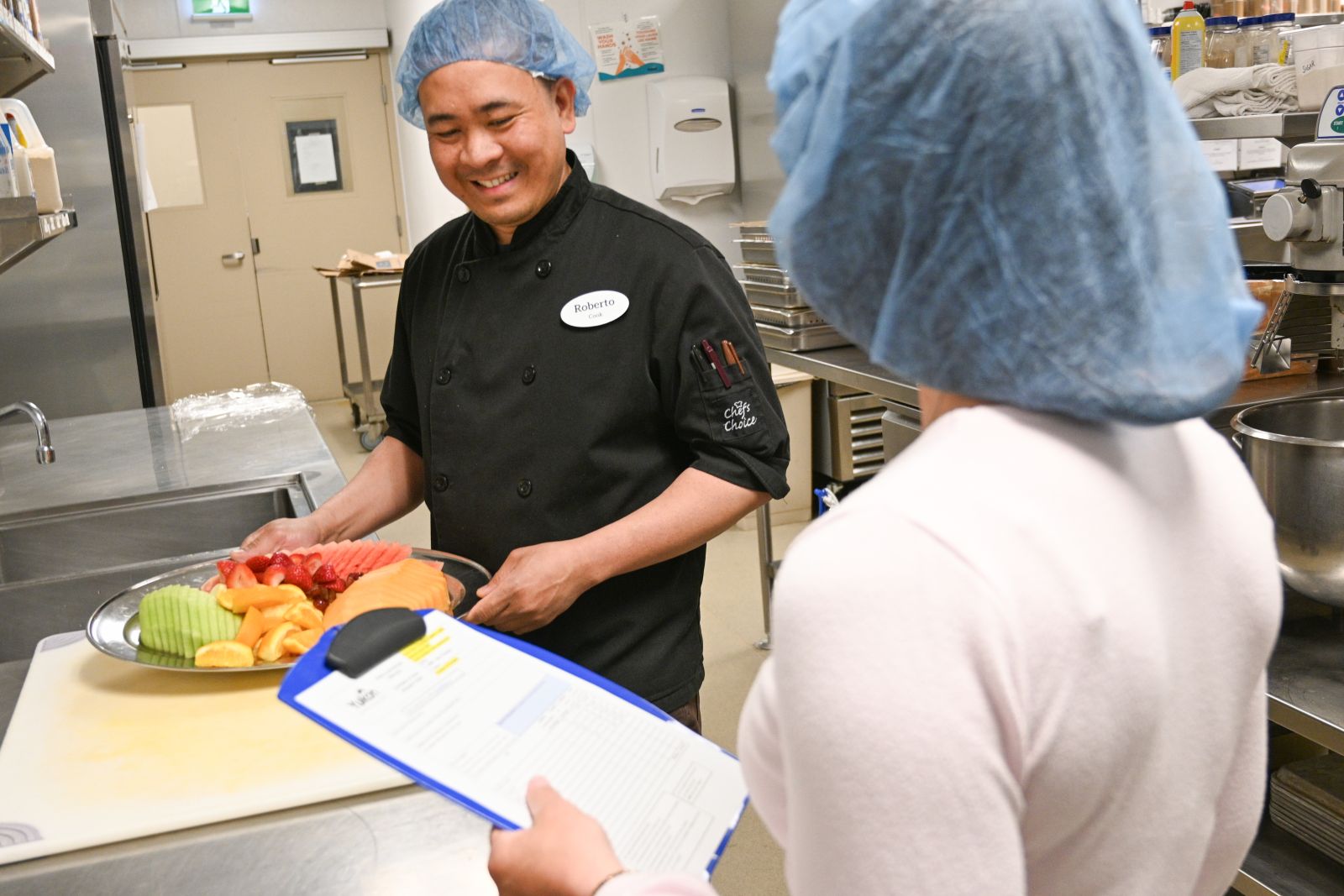 Two cooks are shown in the kitchen at Whistle Bend Place in Whitehorse