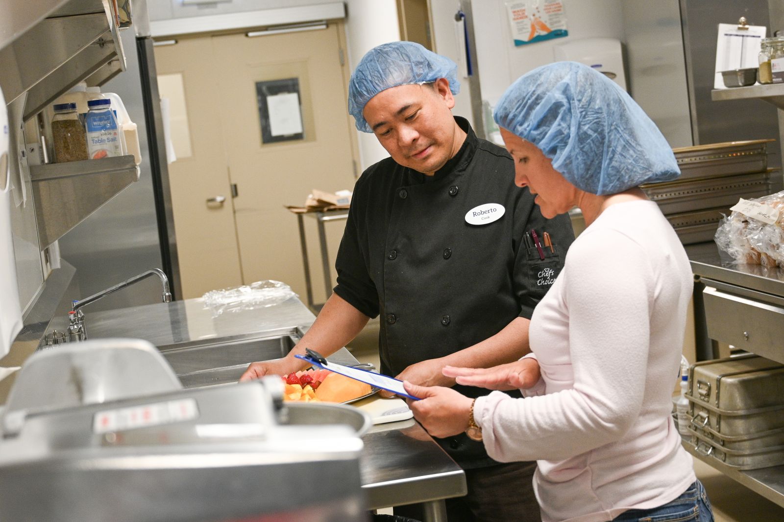 Two cooks are shown working together in a kitchen at Whistle Bend Place