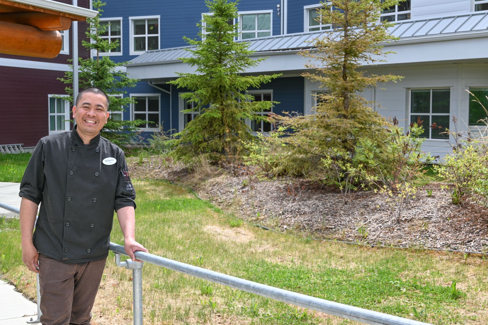 A cook stands outside Whistle Bend Place