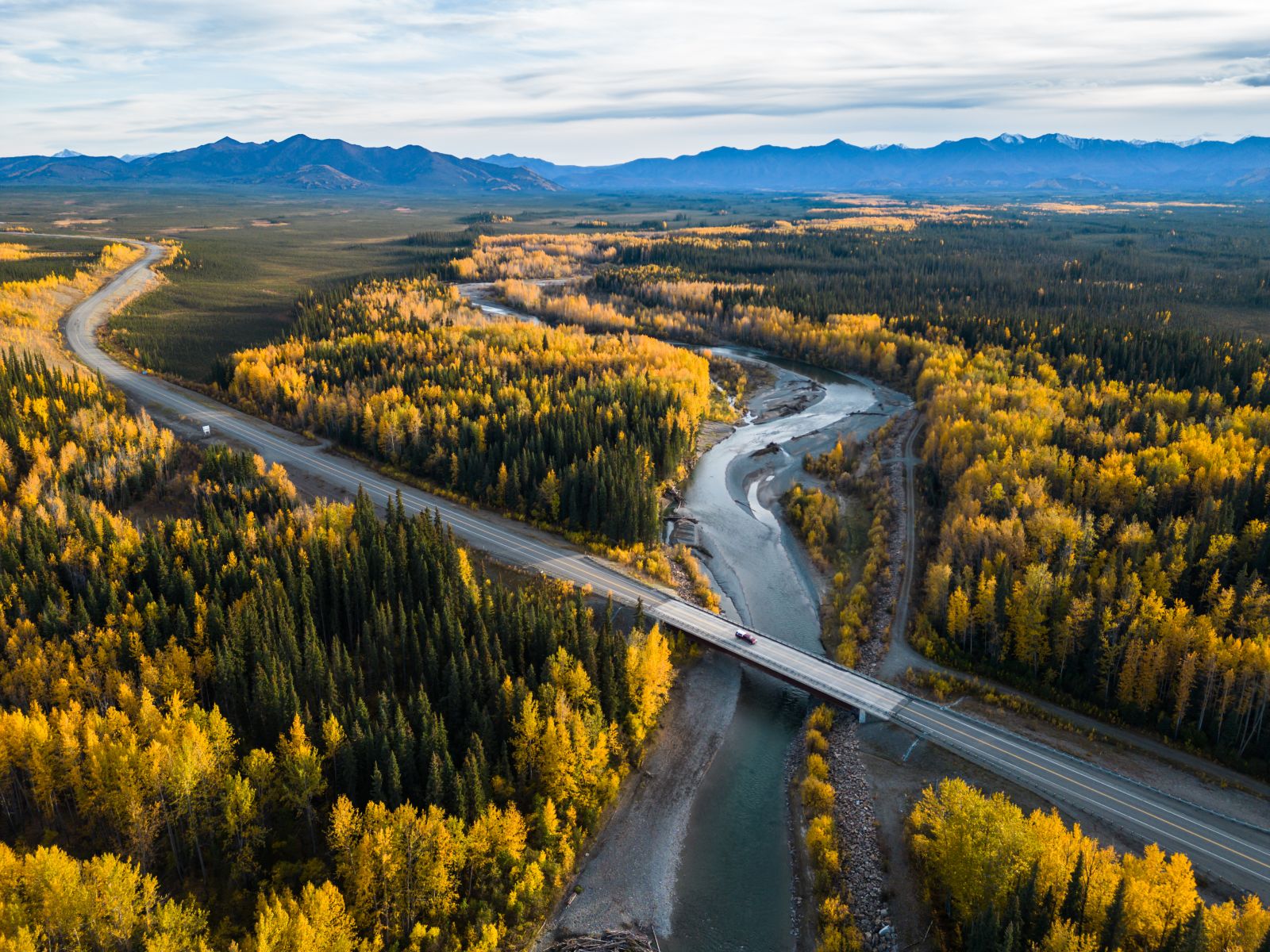 A vehicle crosses the Alaska Highway bridge over Beaver Creek as it drives westward toward the Canada-USA border and Beaver Creek.