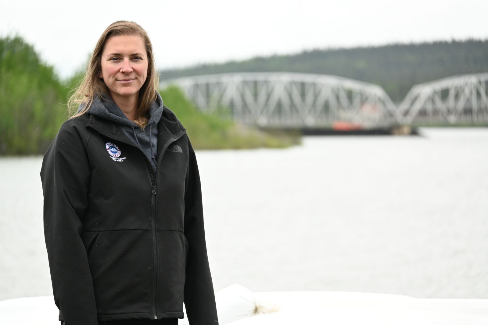 Camille, an administrative assistant, stands on the shore of Nisutlin Bay in Teslin overlooking the bridge.
