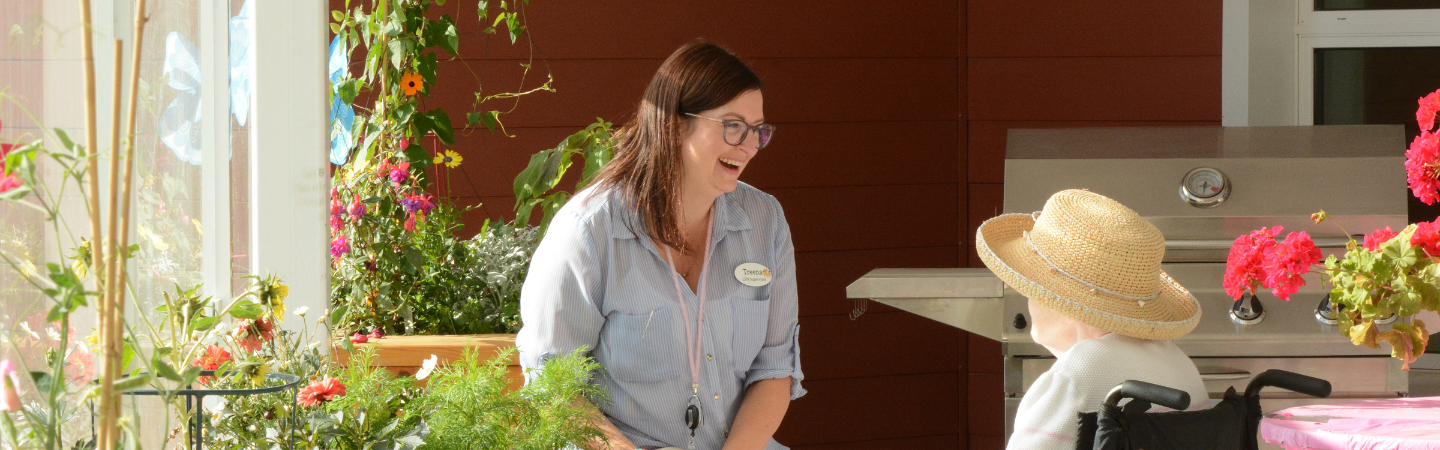 A conversation is shown between a health care worker and resident of Whistle Bend Place on a balcony