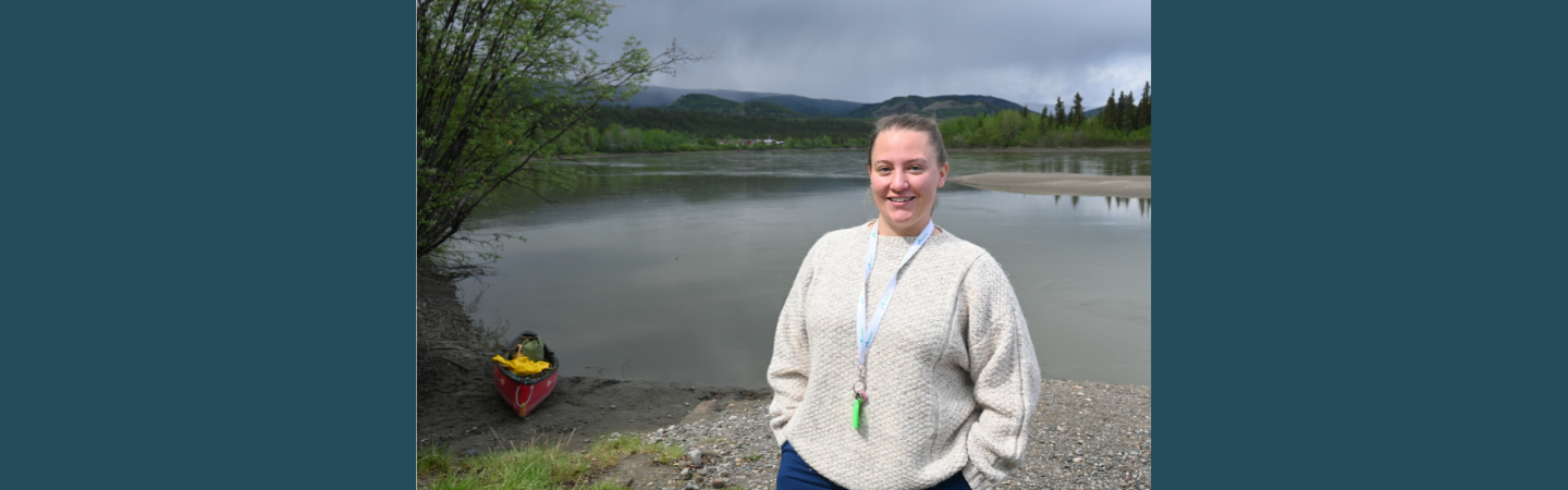 A nurse stands on the shore of the Yukon River in Carmacks, Yukon