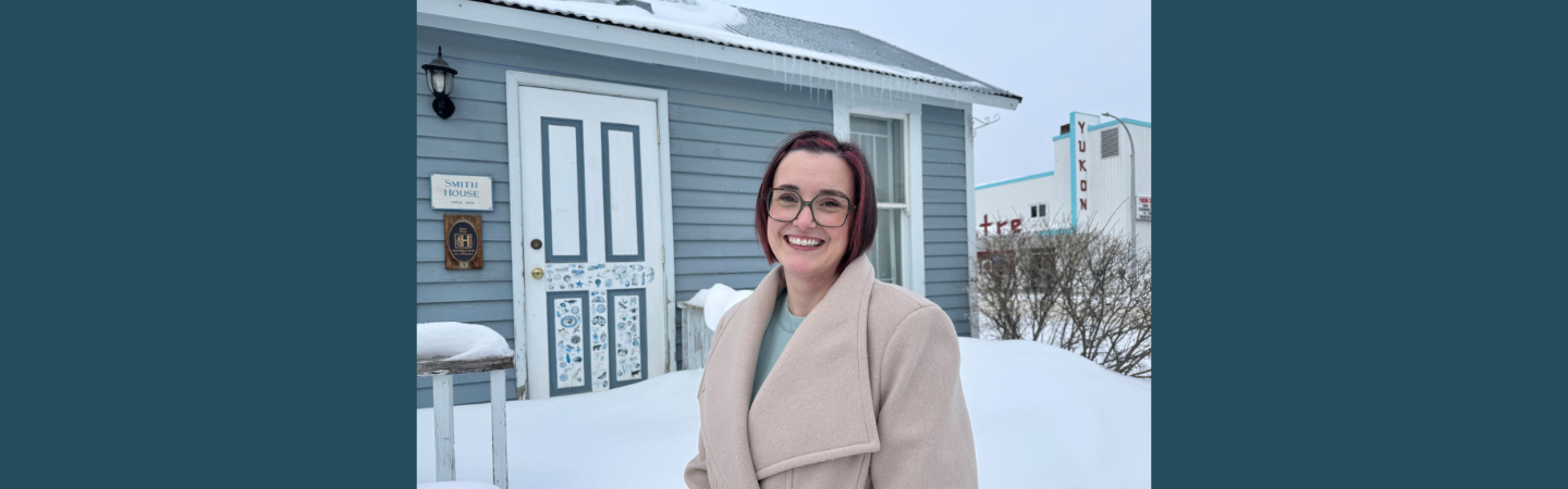 A social worker in the Yukon stands outdoors near a historic building